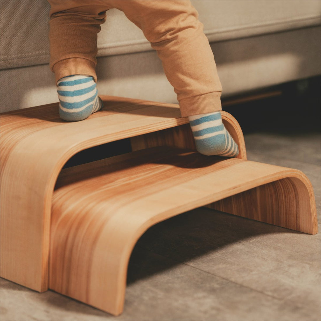 1. Child stepping on wooden step stool with striped socks in a cozy indoor setting