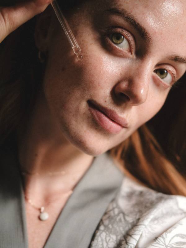 1. Woman applying LUUV Anti-Aging Bakuchiol Serum to her face, showcasing skincare routine