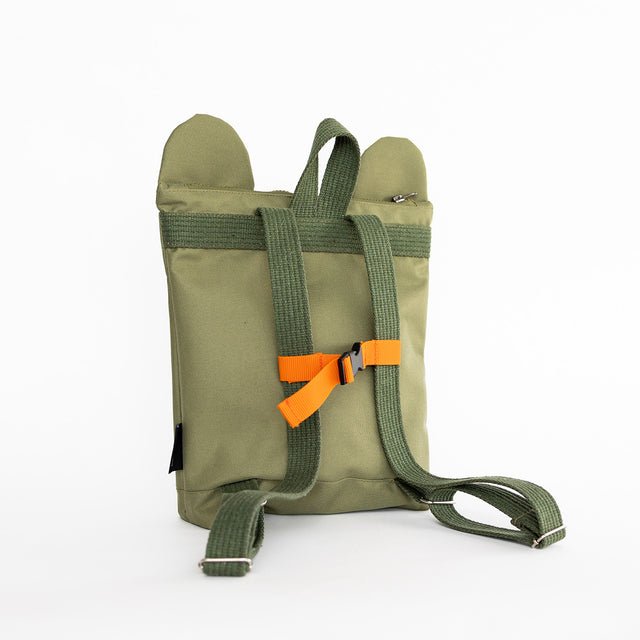 3. Child holding Muni Green Bear Backpack near a lake, emphasizing stylish and playful look