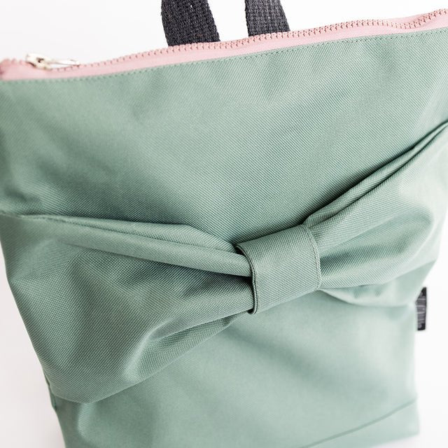 8. Close-up of Muni kids mint bow backpack interior with 'Let's Go Outside!' label