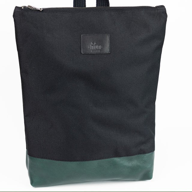 7. Studio shot of Muni waterproof backpack with green leather bottom, highlighting front design and logo