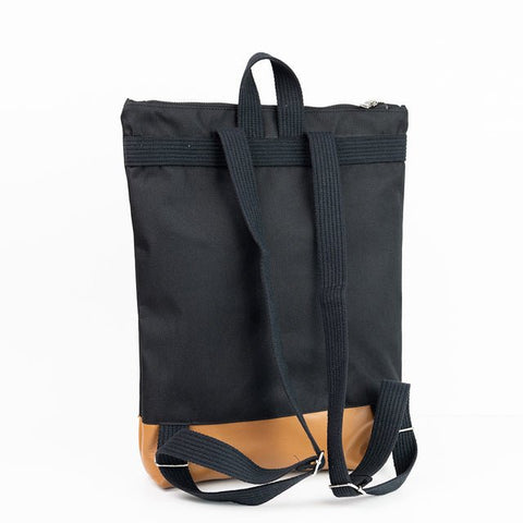 4. Back view of Muni waterproof backpack with tan leather bottom, showing adjustable straps in studio setting