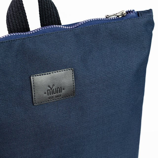 7. Close-up of Muni logo and zipper on navy blue waterproof backpack