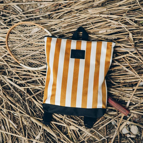 4. Muni striped mustard and white backpack on straw with a badminton racket