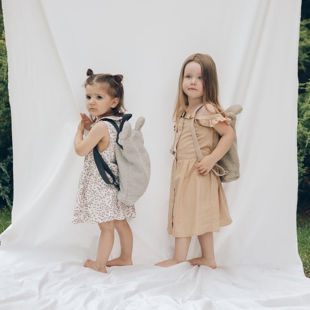 1. Two young girls wearing Muni grey teddy backpacks, showcasing adjustable straps and playful design in a lifestyle setting