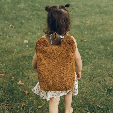 2. Toddler walking with Muni brown teddy backpack in park, highlighting eco-friendly material and cute bear ears