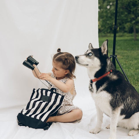 2. Child with Muni black and white striped backpack and dog in outdoor setting