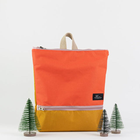 2. Muni kids backpack in orange and yellow, lifestyle image with mini trees, highlighting adventure theme