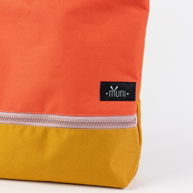 5. Close-up of Muni logo on orange and yellow waterproof kids backpack