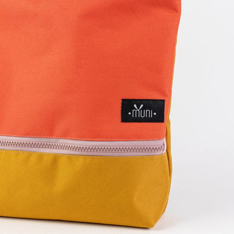 5. Close-up of Muni logo on orange and yellow waterproof kids backpack