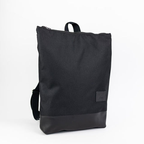 5. Studio image of Muni waterproof backpack with black leather bottom, featuring front view and brand logo