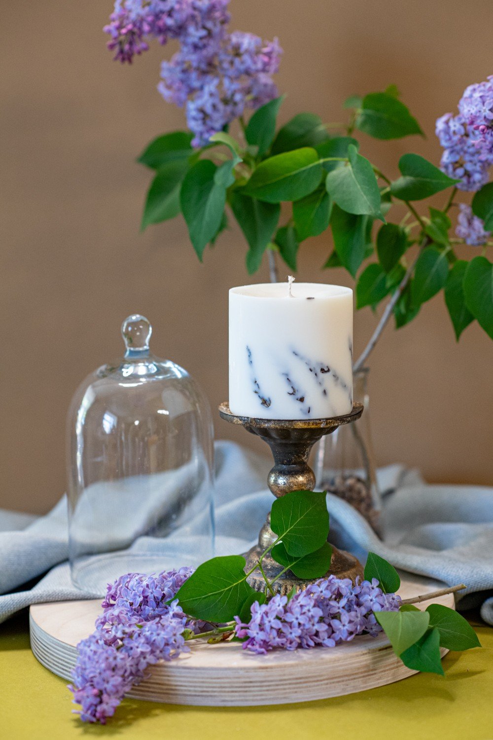 1. Hand-made white soy wax candle with lavender scent on a decorative stand, surrounded by lavender blossoms, lifestyle setting