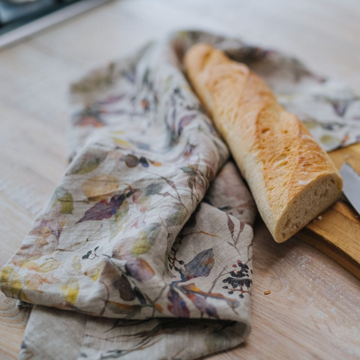 8. Floral print linen kitchen towel on wooden surface with baguette