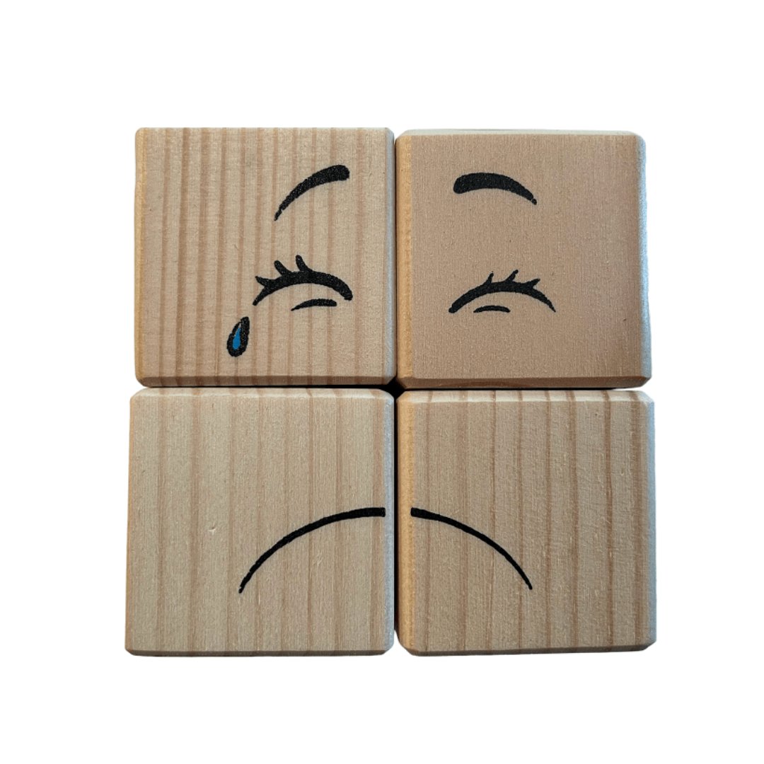 3. Four pinewood blocks showing a sad face with a tear and closed eyes, part of ROOSI Traditional Toys' Special Expressions Blocks for Kids