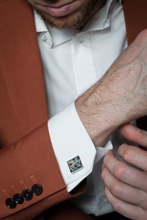 1. Man wearing white shirt and brown suit adjusting cuff with Eherüs square cufflink made from red-spotted brown trout leather