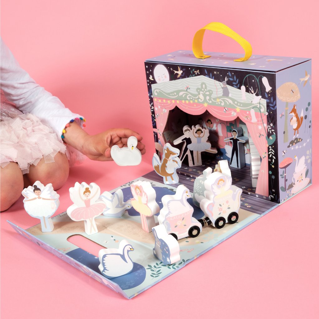 1. Child playing with Floss & Rock enchanted playbox featuring wooden ballerinas and swans on a pink background