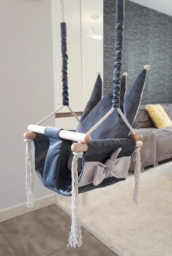 1. Grey crown-shaped cushion swing for children with velvet plush material and pinewood frame, hanging in a modern living room setting