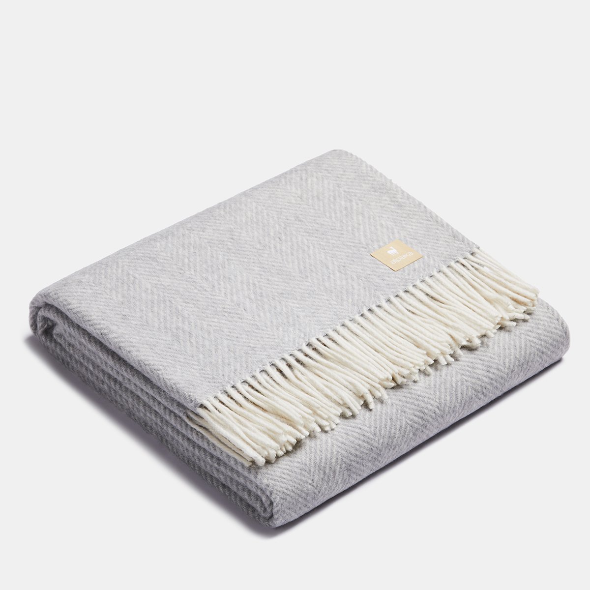 5. Folded light gray Alpaka wool throw with fishbone pattern and fringe in studio