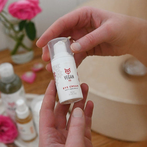 2. Vegan Fox Anti-Wrinkle Eye Cream held by woman, surrounded by skincare products and pink roses