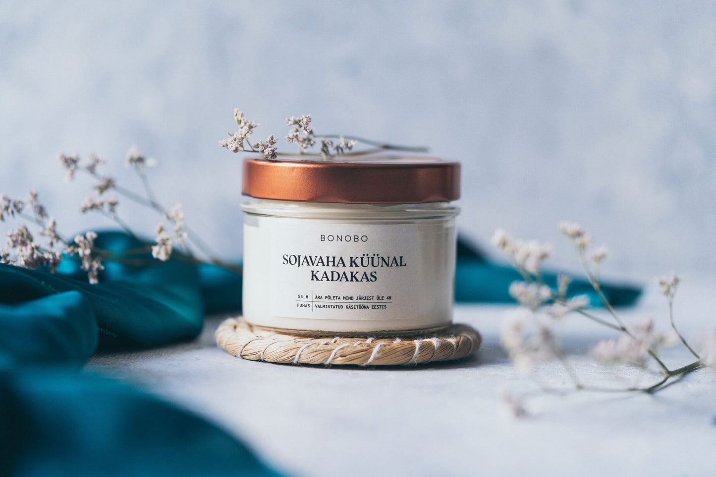 3. BONOBO juniper scented candle in a glass jar with copper lid, styled with dried flowers in a serene setting