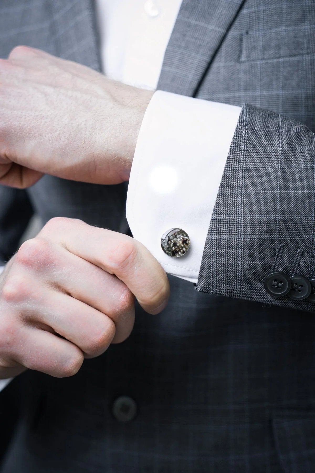 1. Man adjusting cuff of grey suit jacket with Eherüs black-spotted leather cufflink