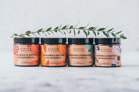 2. Collection of BONOBO body scrubs including Blueberry and Lavender, displayed with greenery, studio setting