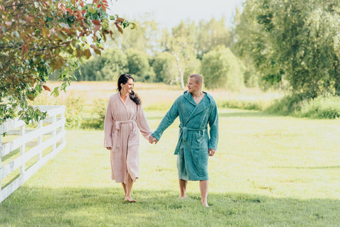 1. Unisex bamboo terry bathrobes worn by a couple walking in a garden, showcasing pink and teal colors