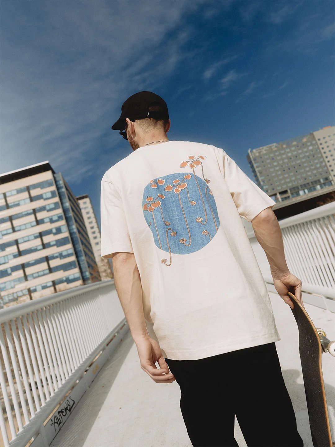 1. Men's heavy-weight premium t-shirt 'Bijutsu Sekai' by Watanabe Seitei, worn by male model with skateboard, showcasing vine illustration, lifestyle setting