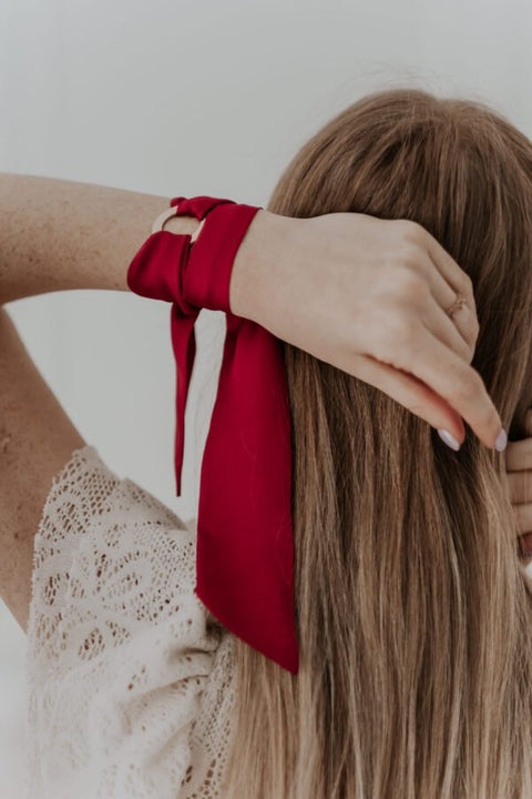 1. Woman wearing Olla Silk Ribbon Bracelet in dark red, styled as a hair accessory, showcasing satin finish and stainless steel ring