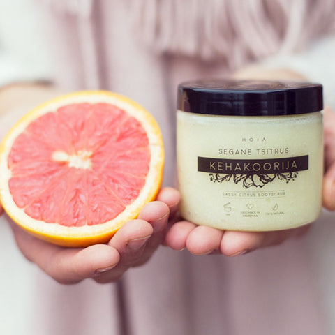 1. HOIA homespa Sassy Citrus body scrub held by a person alongside a fresh grapefruit, highlighting natural ingredients and uplifting aroma