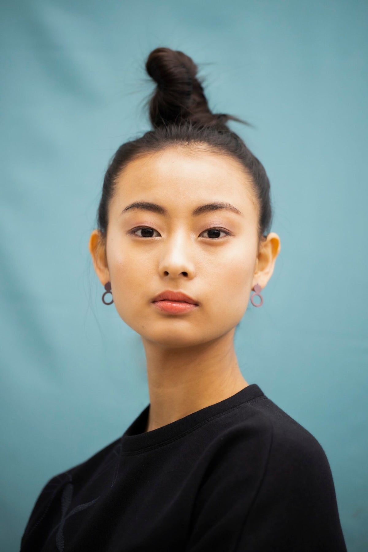 3. Front view of woman wearing Lentsius Arc Purple earrings, emphasizing sustainable craftsmanship