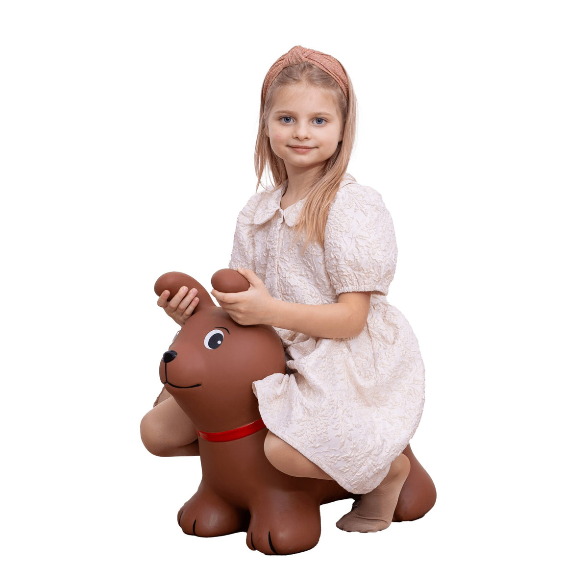 3. Girl in white dress sitting on brown dog-shaped hopper toy against black background