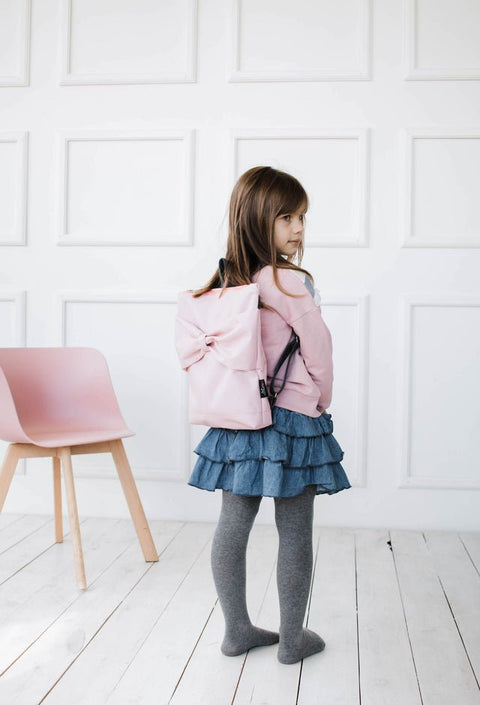 1. Girl wearing Muni pink bow kids backpack in lifestyle setting