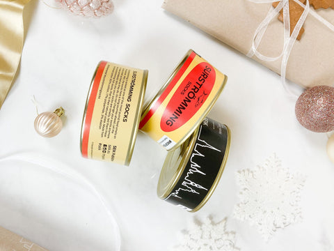 3. Close-up of SEIK Socks in a Tin Can Gift Set, highlighting Surstrƶmming and Tallinn designs with festive decor