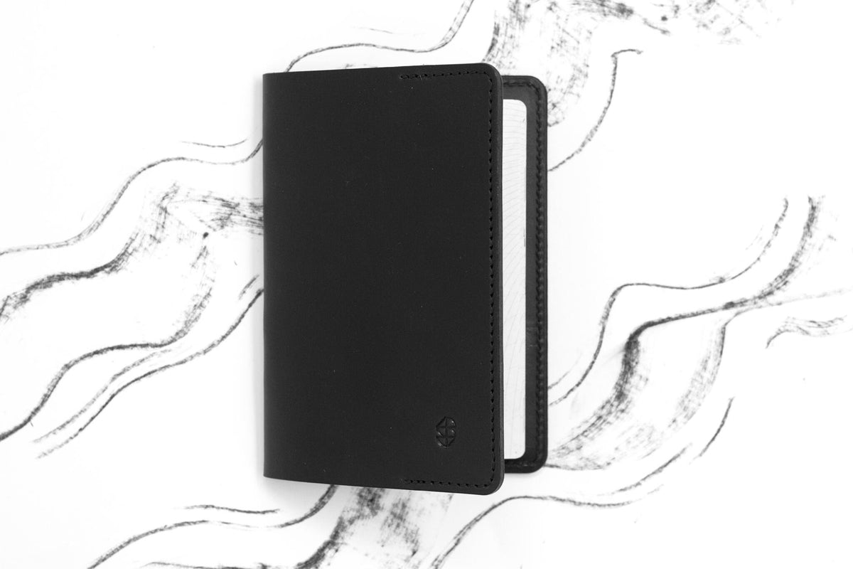 3. Closed black leather passport cover by Stella Soomlais on white background with abstract lines