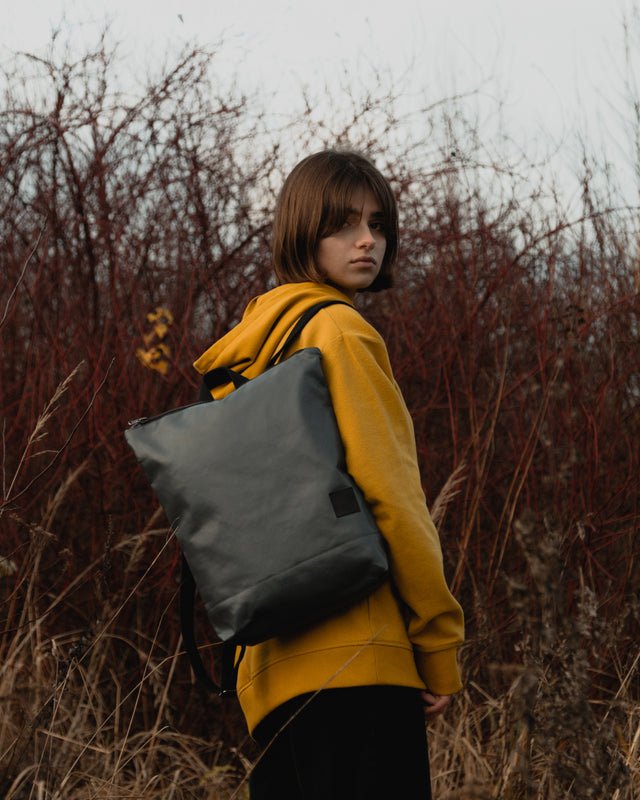 1. Woman wearing Muni faux leather grey backpack in outdoor setting