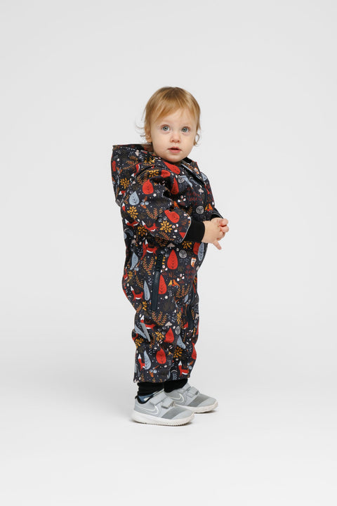 4. Toddler in Nuckö softshell onesie with forest print, standing sideways in studio