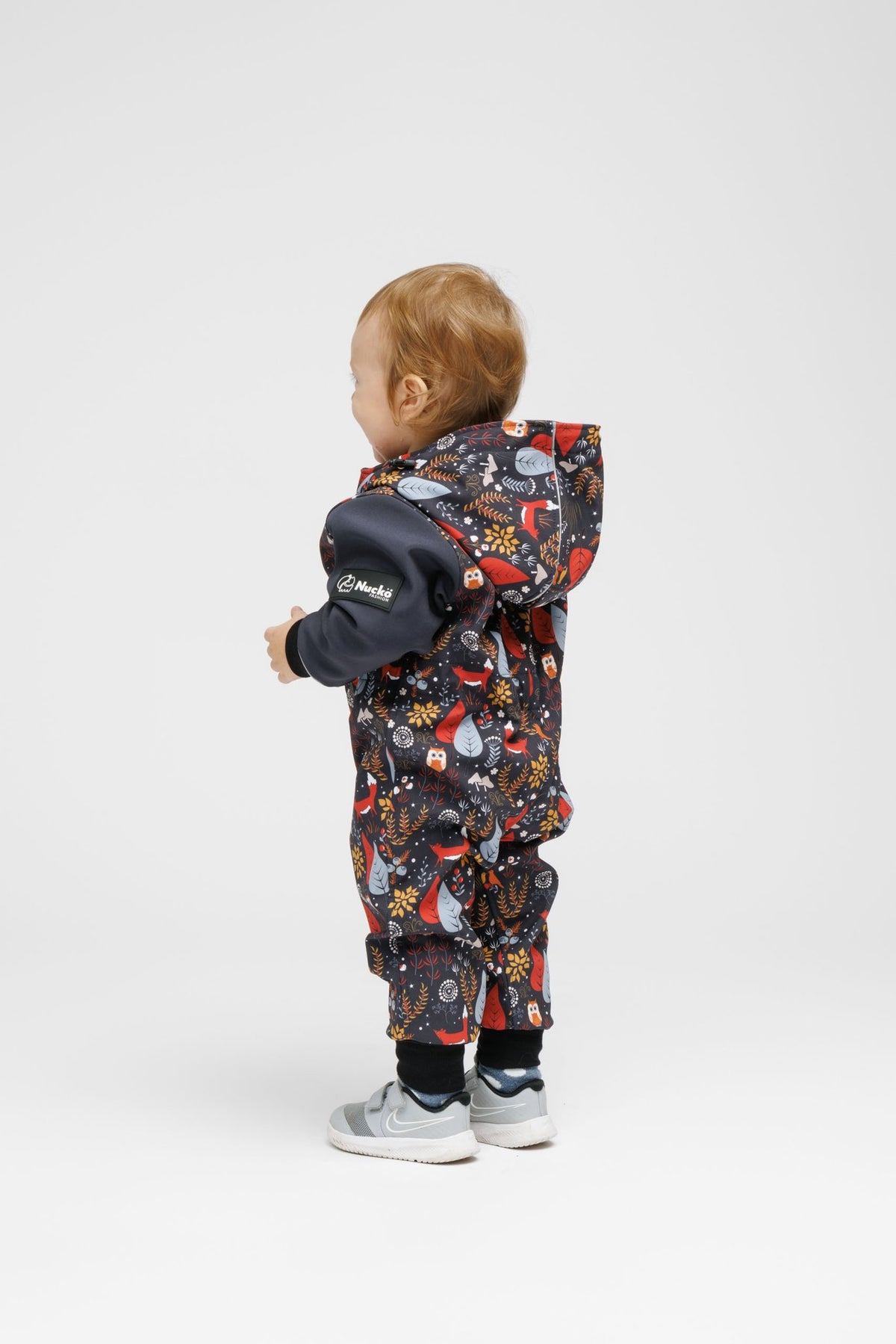 3. Toddler in Nuckö softshell onesie with forest print, side view in studio