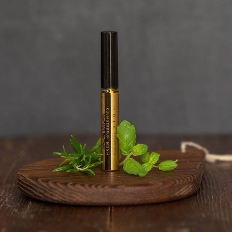 2. HOIA homespa Brow Serum bottle on a wooden surface with fresh herbs, highlighting natural ingredients and eco-friendly packaging