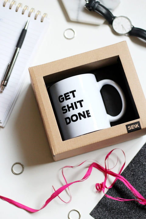 1. SEIK Design Mug with 'GET SHIT DONE' text in gift box, shown in lifestyle setting with office accessories