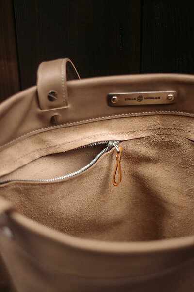 3. Close-up of beige leather tote bag interior with zipper pocket and Stella Soomlais logo