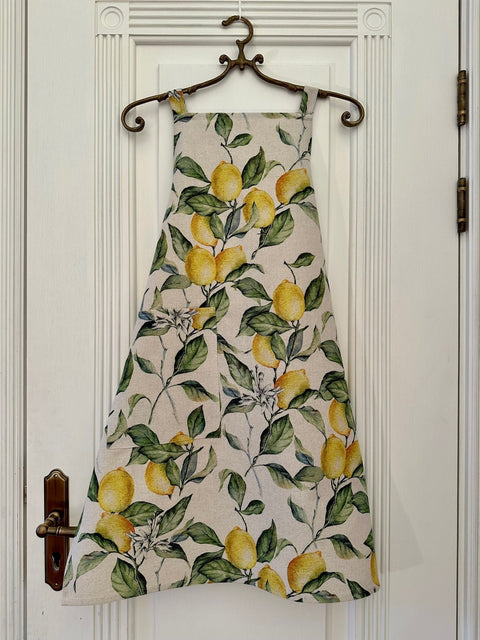 1. Ladies' apron in lemon linen with vibrant lemon print, hanging on a door, showcasing European craftsmanship by Hortensias Home