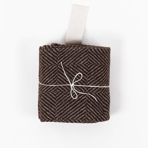 3. Rolled brown linen towel with checkered fishbone pattern tied with string and white cotton hanger on white background