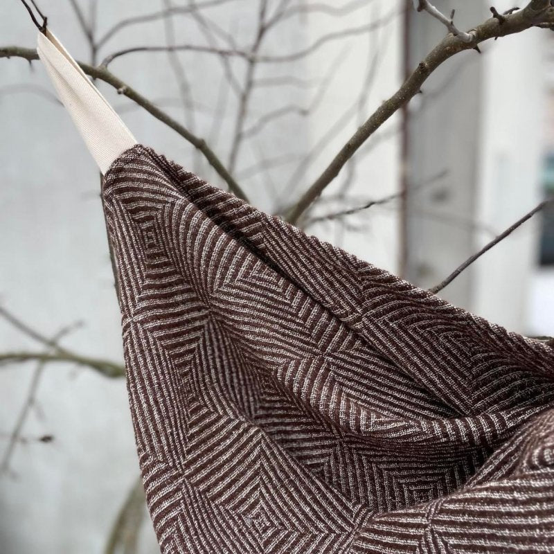 1. Brown linen towel with checkered fishbone pattern hanging on a branch outdoors