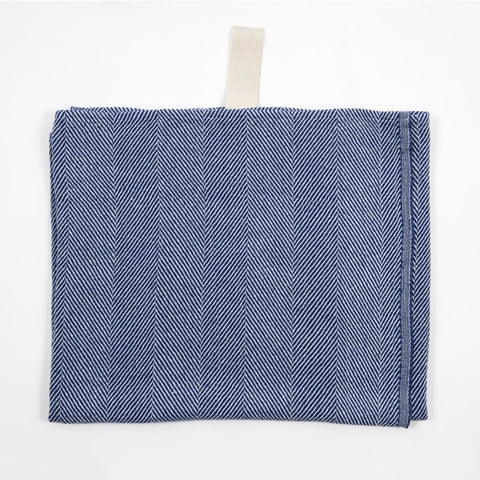 2. Blue linen towel with fishbone pattern and white hanger laid flat on white background