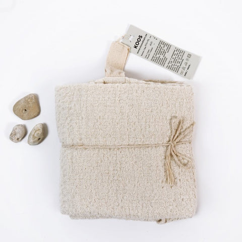 3. KOOSdisain big linen towel in textured white fabric folded with label and small stones