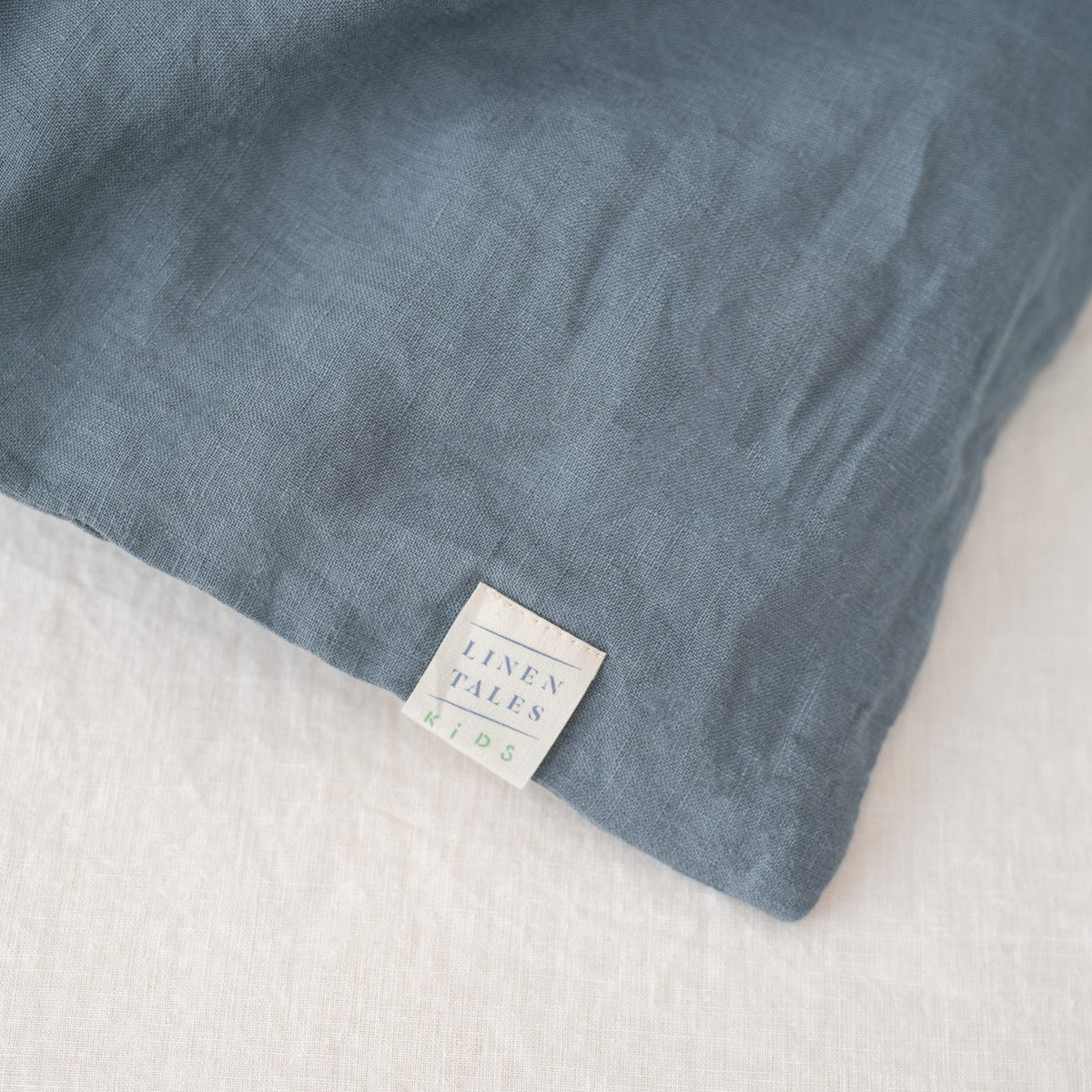 3. Close-up of Linen Tales label on blue fog linen duvet cover, highlighting brand and fabric texture