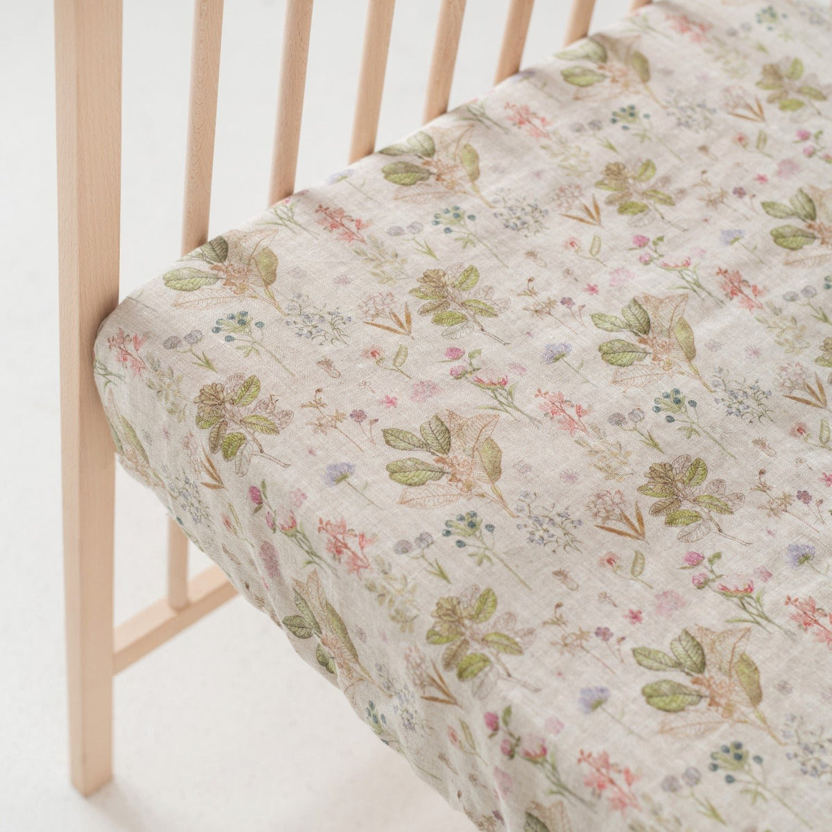 4. Close-up of floral linen fitted sheet on crib mattress with wooden crib slats