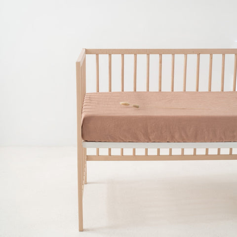 2. Cafe creme linen fitted sheet on crib in a bright room, emphasizing the snug fit and smooth surface