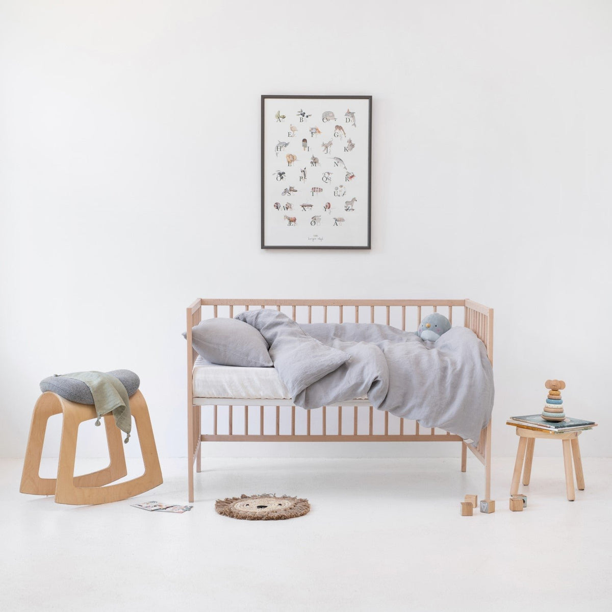 1. Light grey linen duvet cover set on a crib in a minimalist children's room with wooden furniture and decor